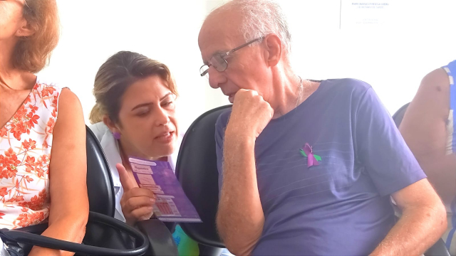 A farmacêutica Juliana Marques explica sobre a doença a um paciente